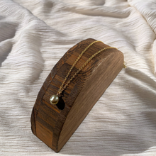 Load image into Gallery viewer, A necklace with a green fresh water pearl on a 14k gold-filled chain, displayed on a textured white background.